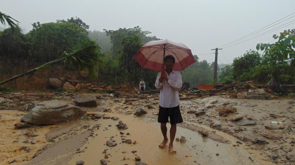 mot nguoi dan ong dung che ô trong trận mưa lũ tại Bắc trà my