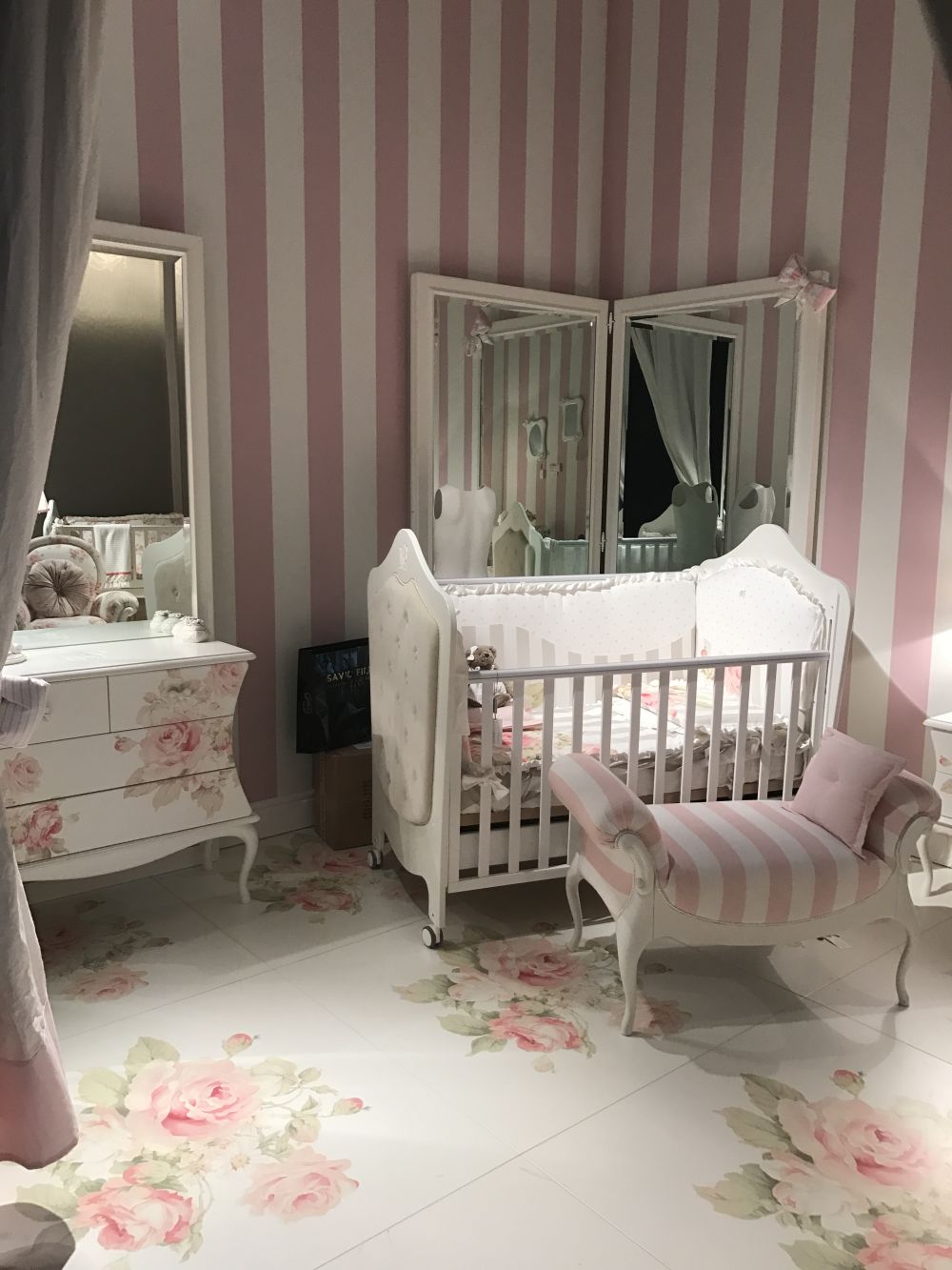 Nursery room with pale pink accents and floral patterns on floor and furniture