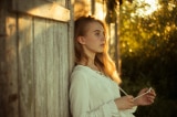 woman wearing white top leaning on wooden wall 2726046