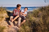 man and boy sitting on floor near body of water 1161442