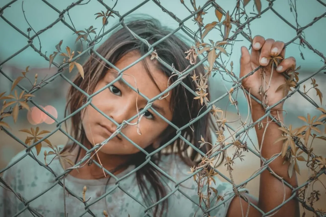 girl s white and gray crew neck top holding gray wire fence 1098769 image