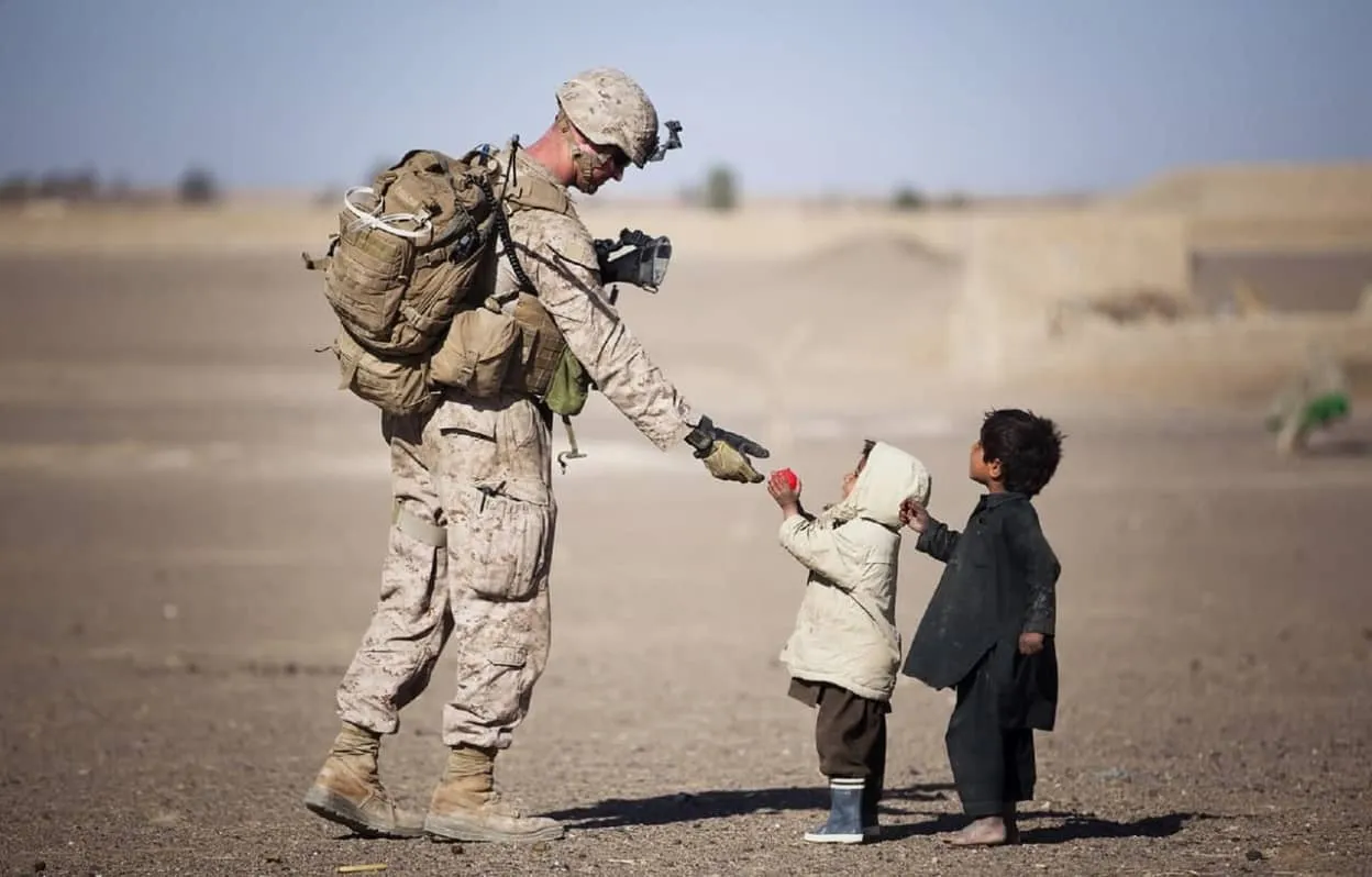 soldier giving red fruit on 2 children during daytime 36785 image