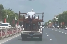 Xe bán tải biển xanh chở người ngồi ngất ngưởng trên chồng bàn ghế